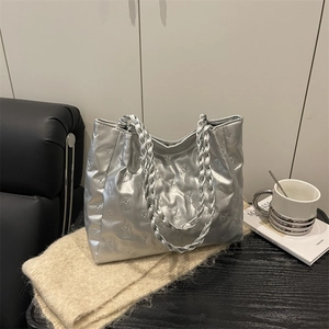 Silver bear-quilted large tote bag with braided handles on a stylish sofa