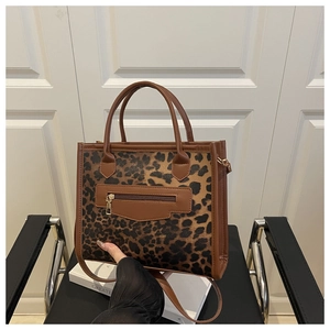 Detailed view of leopard print tote bag with brown leather handles and golden hardware