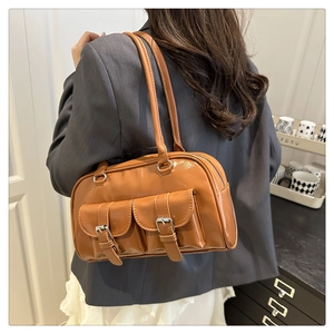 Macro shot of brown faux leather shoulder bag featuring silver buckle front pocket detail