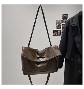 Detail of dark brown PU leather tote with woven strap and smooth texture finish