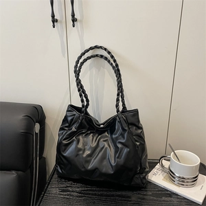 Minimalist black quilted tote bag with unique woven handles for a stylish casual look