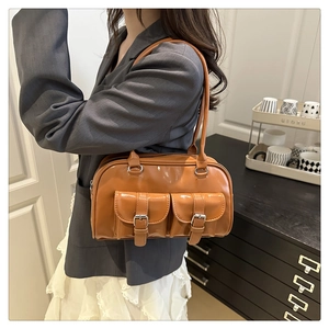 Detail view of caramel brown glossy shoulder bag with double buckle pockets and strap
