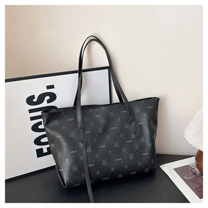 Detail of black tote bag featuring monogram pattern and soft lychee grain leather texture