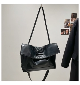 Detail of minimalist black PU leather tote with rope strap and oval cutout handle
