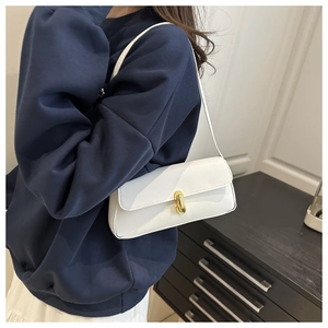 Nahaufnahme der weißen Lychee-Ledertextur und des goldenen Metalldrehverschlusses der Tasche