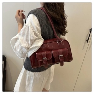 Detail view of burgundy patent leather bag with silver buckles worn by a model