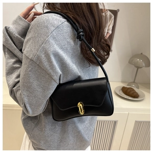 Close-up of the black matte leather shoulder bag with a gold egg-shaped twist lock buckle