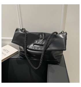 Detail of the black PU leather tote bag featuring a textured soft finish and braided straps