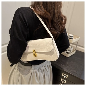 Detailed view of white crocodile texture leather and golden metal clasp on shoulder bag