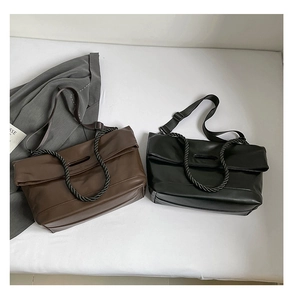 Detail view of large PU leather tote bags in black and dark brown with woven handles