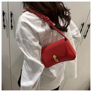 Red faux leather shoulder bag with a gold oval lock and knotted strap detail worn by model
