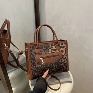 Chic leopard print handbag with brown leather trim and metal zipper on white stand