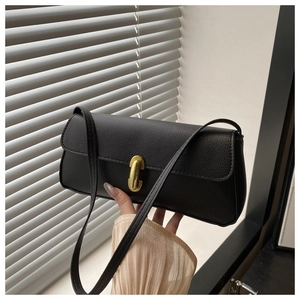 Detail of black lychee grain leather bag featuring a gold U-shaped metal lock and slim strap