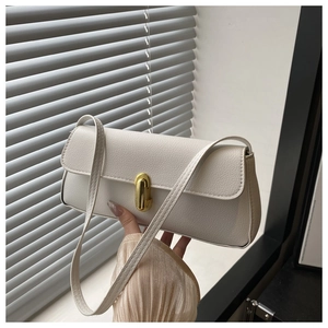 Close-up of white pebble leather baguette bag with a golden square metal clasp lock