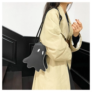 Ghost-shaped black crossbody bag with white contrast piping shown on a trench coat model