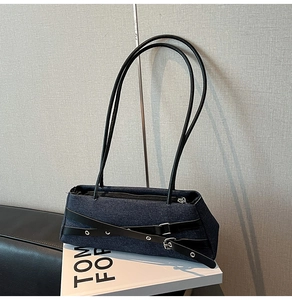Detailed macro of denim shoulder bag featuring crossover leather straps and metal buckles