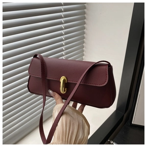 Detail view of burgundy pebble leather bag with elegant oval gold metal buckle and strap