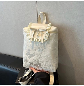 Detail of ruffled edges, 3D bow, and pearl charm on a cream-colored polka dot backpack