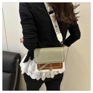 Detail of color-block crossbody bag with sage green tones and bohemian embroidered strap