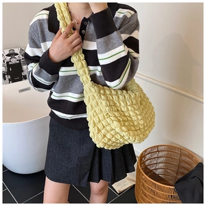 Detail of soft yellow textured puff shoulder bag showing pleated cloud pattern on strap