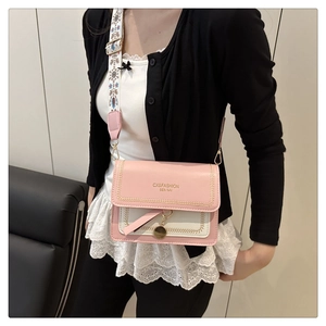Detail of pink and beige crossbody bag with floral embroidery strap and gold hardware