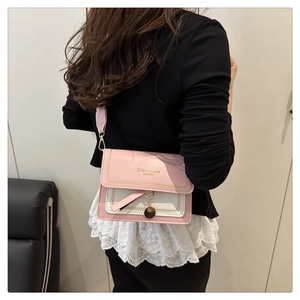 Detail of pink and white crossbody bag with braided trim and metal charm on a model