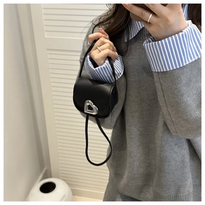 Détail du mini sac bandoulière en cuir noir avec boucle métallique en forme de cœur