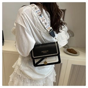Detail view of stylish color-block crossbody bag featuring wide embroidered ethnic strap