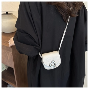 Close-up of white mini crossbody bag with litchi texture and silver heart metal buckle
