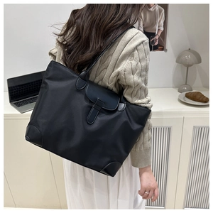 Détail du sac cabas en nylon noir avec rabat magnétique et coins renforcés sur un bureau