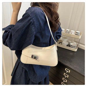 Détail d'un sac sous le bras en cuir beige crème avec un fermoir carré en métal argenté
