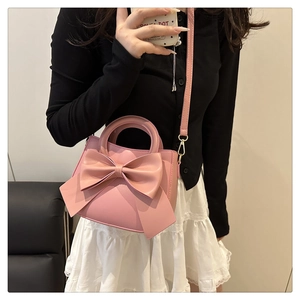 Detailed view of pink PU leather crossbody bag with a large decorative bow and slim strap