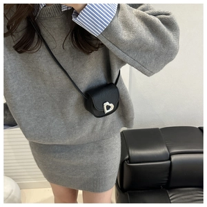 Close-up of black lychee leather crossbody bag with silver heart lock detail on model