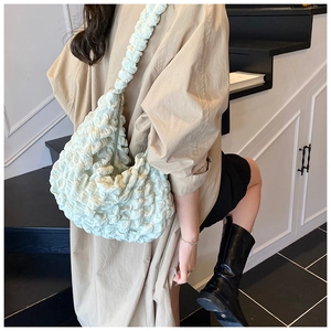 Detail view of light green puffed shoulder bag showing soft pleated fabric texture
