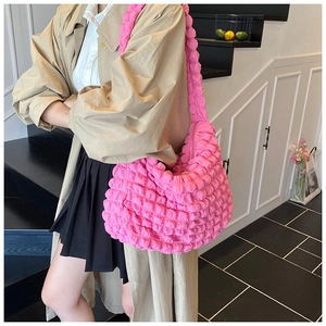 Macro detail of vibrant pink puffy cloud bag showing textured pleats and shoulder strap