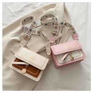 Detail of color-block flap bag with woven trim and ethnic embroidered wide strap