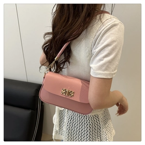 Detail of pink PU leather handbag with golden rotating lock shown on shoulder