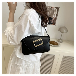 Detailed close-up of a black leather underarm bag with a large gold rectangular buckle
