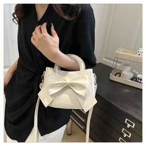 Close-up of white crossbody bag featuring a large bow and detachable shoulder strap