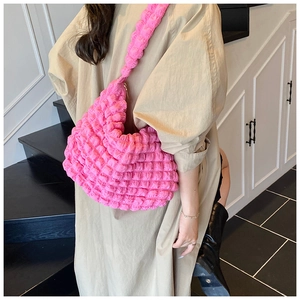 Detail of bright pink pleated cloud bag with soft textured fabric on a stylish model