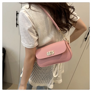 Pink square shoulder bag featuring gold woven lock and chain strap on a model