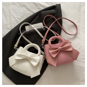 Detail of small crossbody bag featuring a large bow knot and adjustable strap