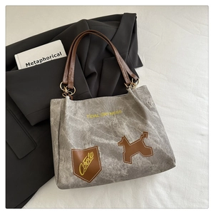 Close-up of gray canvas tote with brown leather handles and dog patch detail