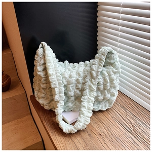 Detail of mint green puffy cloud bag with textured popcorn pleats and wide strap