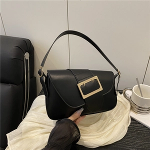 Minimalist black PU leather baguette bag with a large gold buckle and shoulder strap