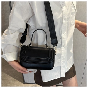Close-up of black saddle bag featuring U-shaped stitching and gold-tone metal buckle