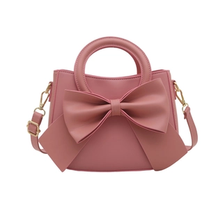 Pink elegant handbag with large bow detail and gold hardware on white background