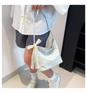 Detail view of light blue daisy plaid tote bag featuring a large cream lace bow accent