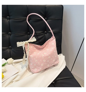 Close-up of pink plaid tote bag featuring white daisy prints and a lace bow detail