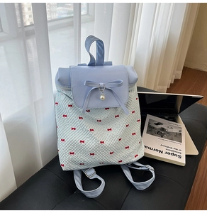 Detailed view of polka dot backpack with blue leather flap, bow and pearl charm